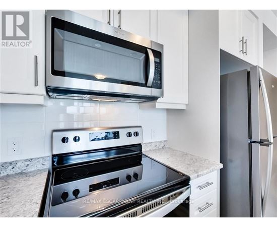 A modern kitchen with a black stove top oven and a black microwave above it.
