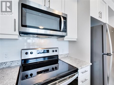 A modern kitchen with a black stove top oven and a black microwave above it.