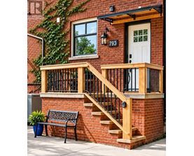 A red brick house with a white door and a black railing on the stairs.