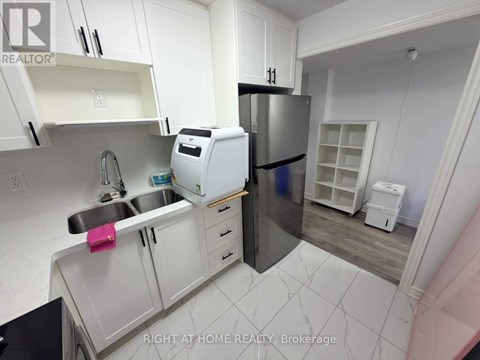A kitchen with white cabinets and a stainless steel refrigerator.