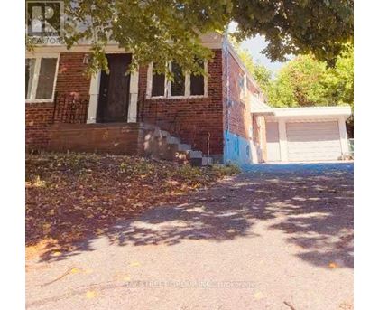 A house with a garage and a tree in front of it.