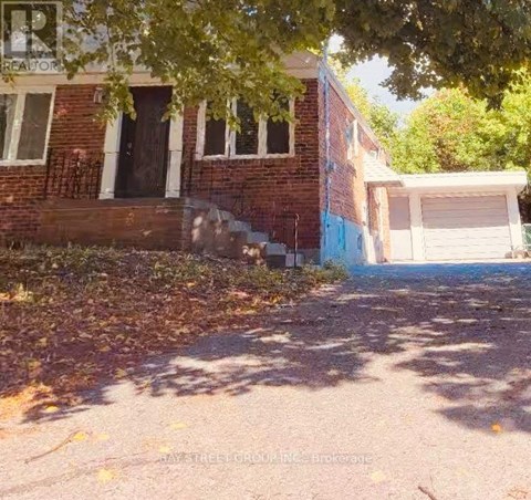 A house with a garage and a tree in front of it.
