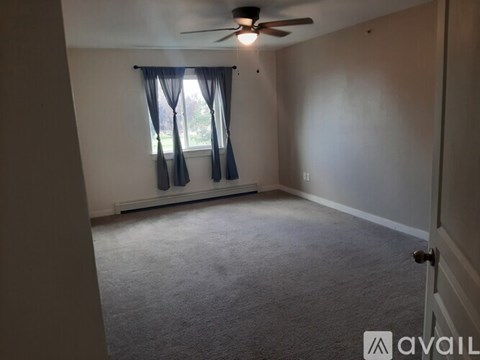 A room with a ceiling fan and carpeted floor.