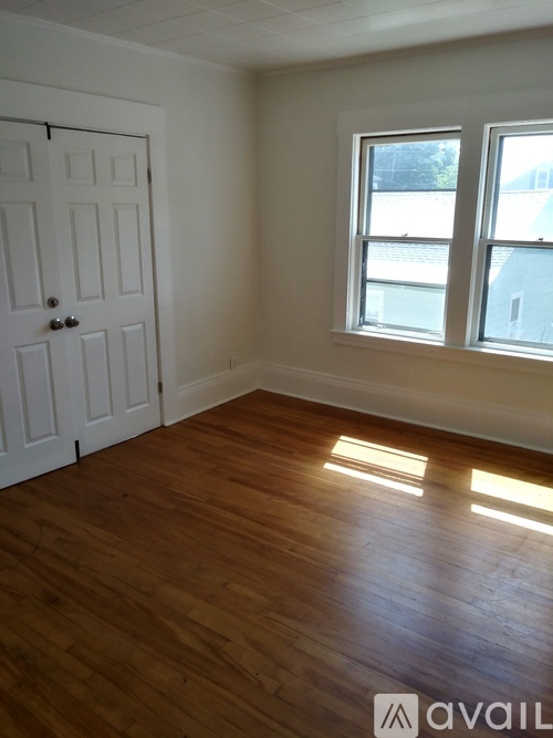 A room with a white door and a window with sunlight shining through.