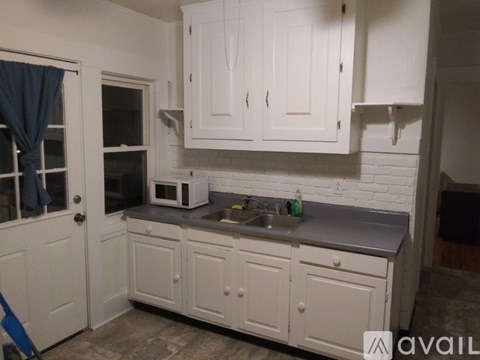 A kitchen with white cabinets and a grey countertop.