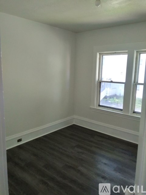 A room with a window and a wooden floor.