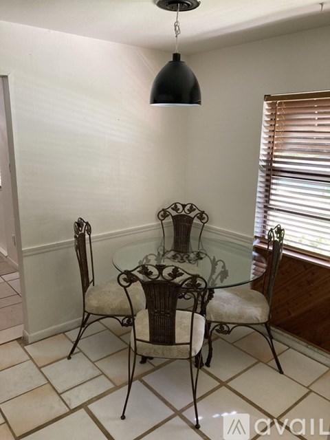 A glass table with four chairs around it.