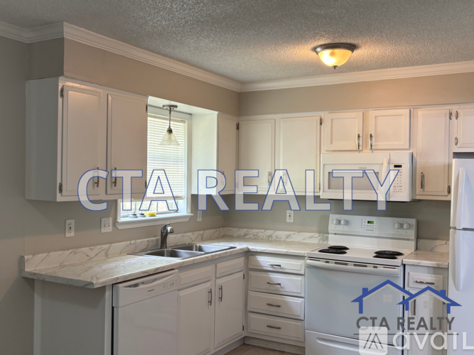 A kitchen with a white stove and cabinets with the words CTA Realty Above it.