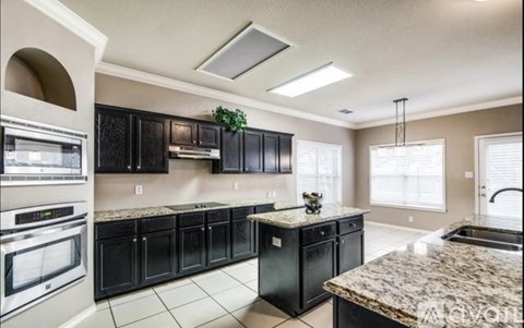 A kitchen with black cabinets and granite countertops.