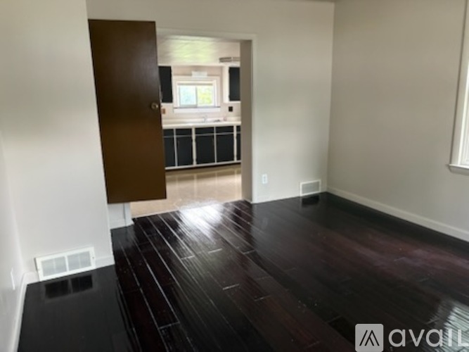 A room with a wooden floor and a door leading to another room.