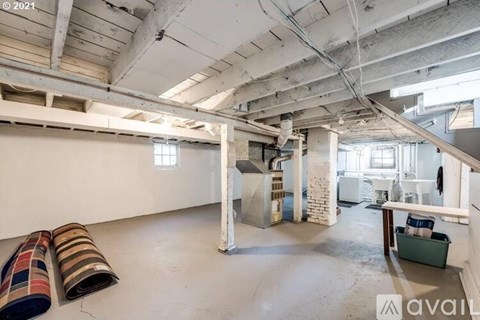 A large, empty industrial space with exposed ceiling beams and a variety of colorful carpet samples on the floor.