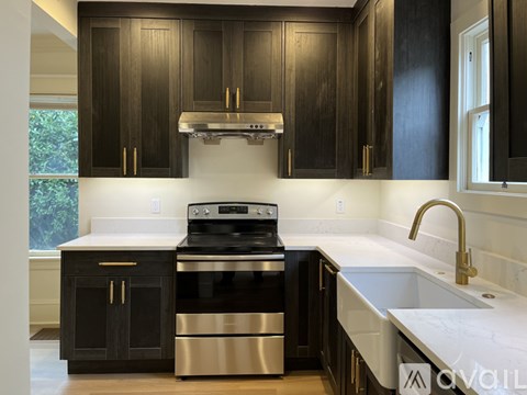 A modern kitchen with black cabinets and stainless steel appliances.