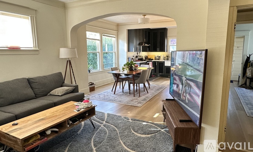 A living room with a grey couch, a wooden coffee table, and a television on a stand.