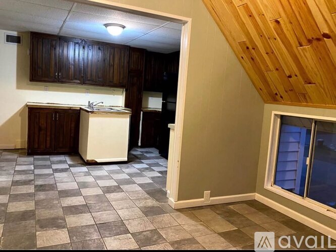 A kitchen with wooden cabinets and a checkered floor.