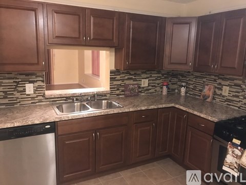 A kitchen with brown cabinets and a stone backsplash.