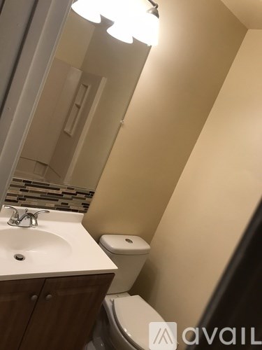 A bathroom with a sink, toilet and mirror.