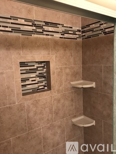A bathroom with a tiled shower and shelves.