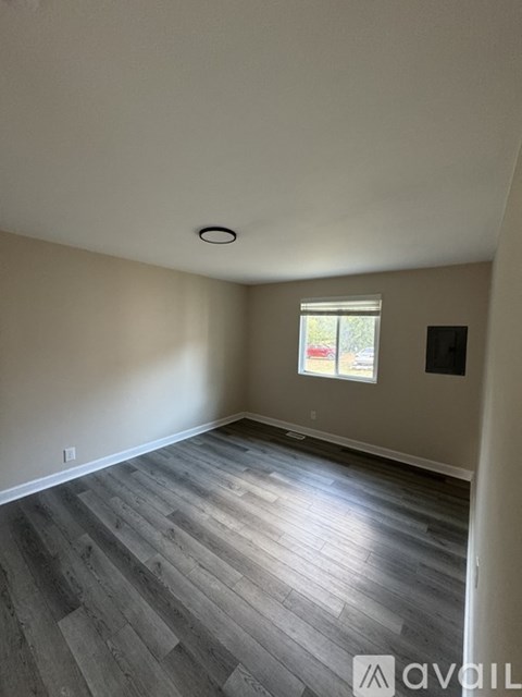 A room with wooden flooring and a window.