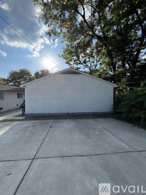 A white garage with a grey roof is situated in a driveway with a concrete surface.