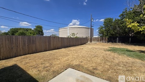 A backyard with a fence and a grassy area.