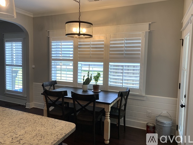 A dining room with a table, chairs, and a plant on the windowsill.