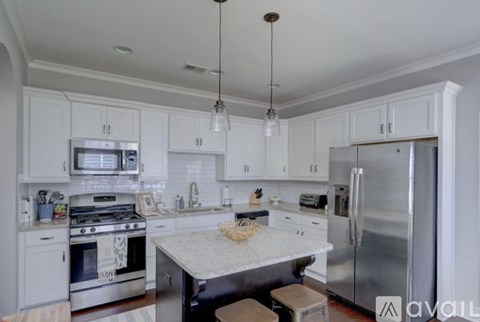 A kitchen with white cabinets and a stainless steel refrigerator.