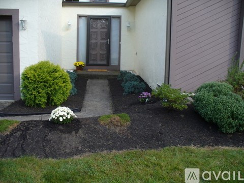 A front yard with a dark brown door and a small garden with white flowers.