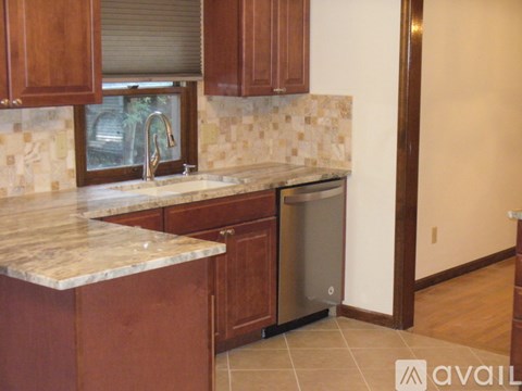 A kitchen with brown cabinets and a marble countertop.