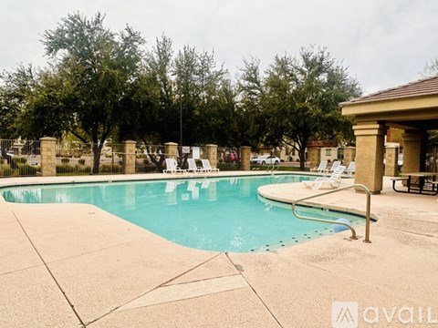 A pool with a brown pavilion and white chairs.