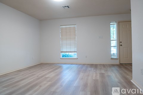 A room with wooden flooring and a window with blinds.