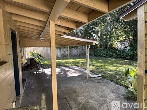 A patio with a table and chairs is covered by a roof.
