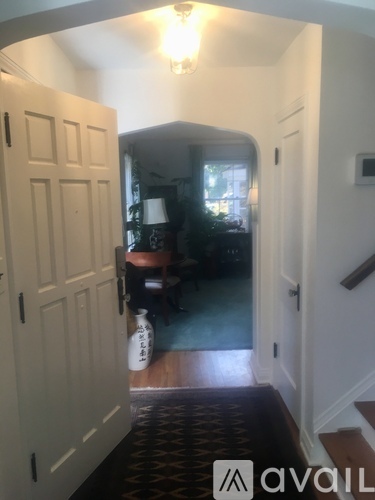 A hallway with a door on the left and a staircase on the right.