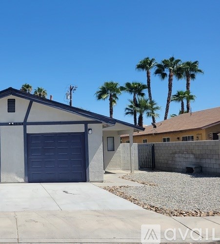 A house with a garage and palm trees in the background.