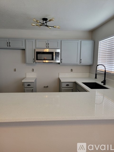 A kitchen with white countertops and cabinets.