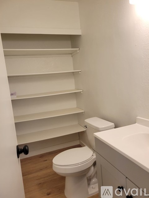 A white toilet sits under a white sink in a small bathroom.