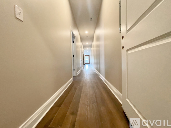 A long hallway with wood floors and white walls.