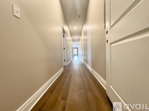A long hallway with wood floors and white walls.