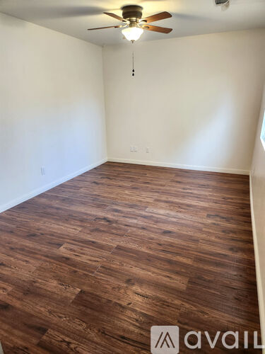 A room with wooden flooring and a ceiling fan.