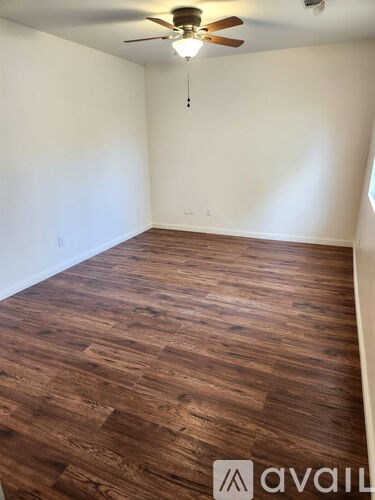A room with wooden flooring and a ceiling fan.