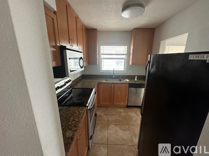 A kitchen with brown cabinets and a black refrigerator.