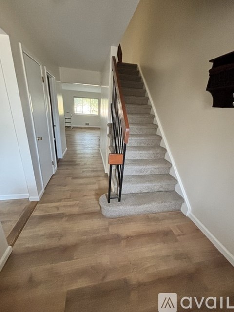 A hallway with a staircase and wooden flooring.
