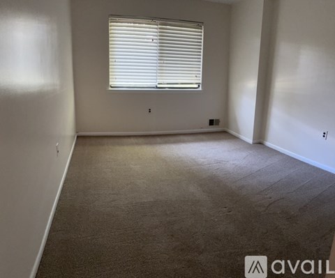 A room with a window covered by white blinds.