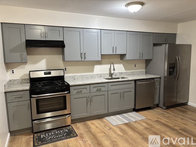 A kitchen with grey cabinets and a stainless steel refrigerator.