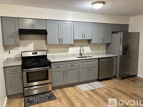 A kitchen with grey cabinets and a stainless steel refrigerator.