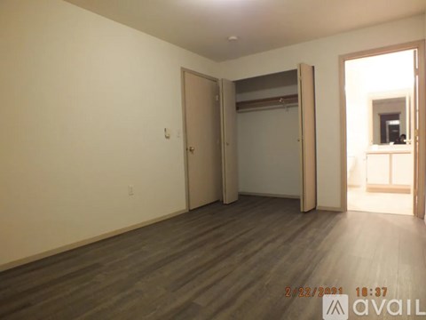 A room with wooden flooring and a doorway leading to another room.