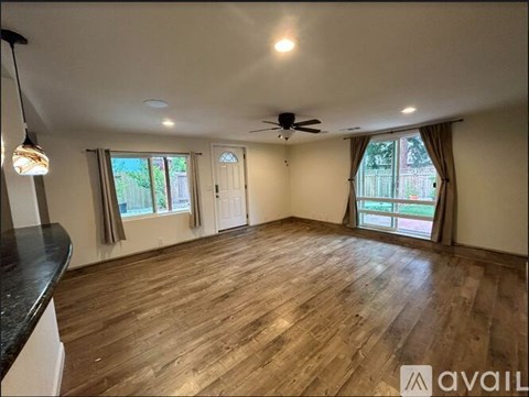 A spacious room with wooden floors and a ceiling fan.