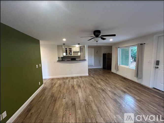 A spacious room with wooden flooring and a ceiling fan.