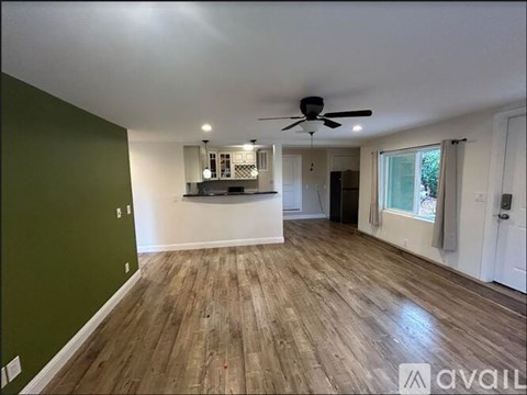 A spacious room with wooden flooring and a ceiling fan.