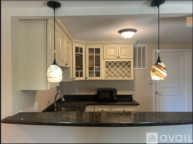 A kitchen with granite countertops and pendant lights.