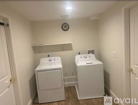A laundry room with two washers and a shelf above them.